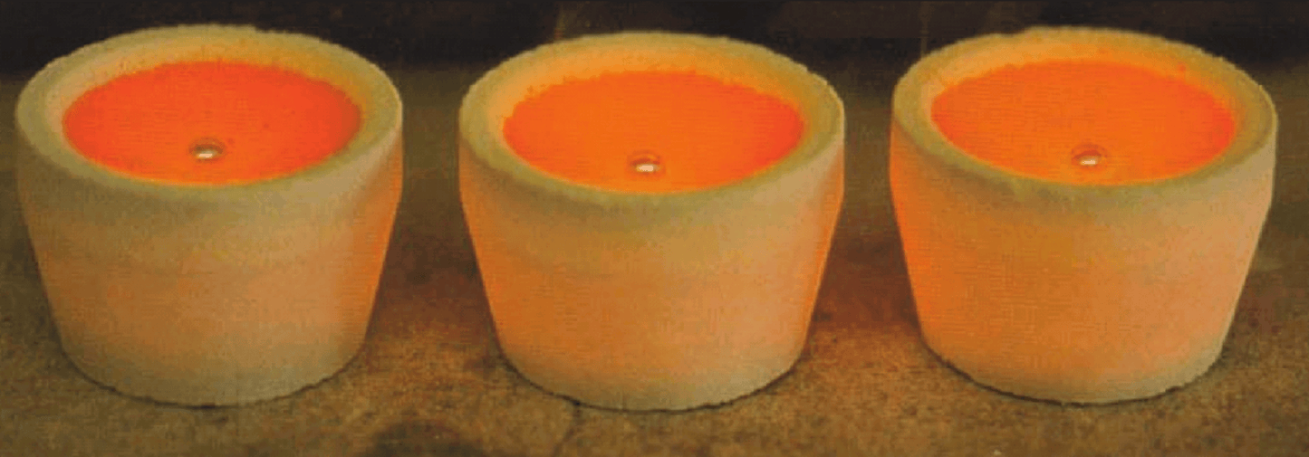 Three magnesia cupels with glowing orange interiors, used for gold and silver refining and assaying.