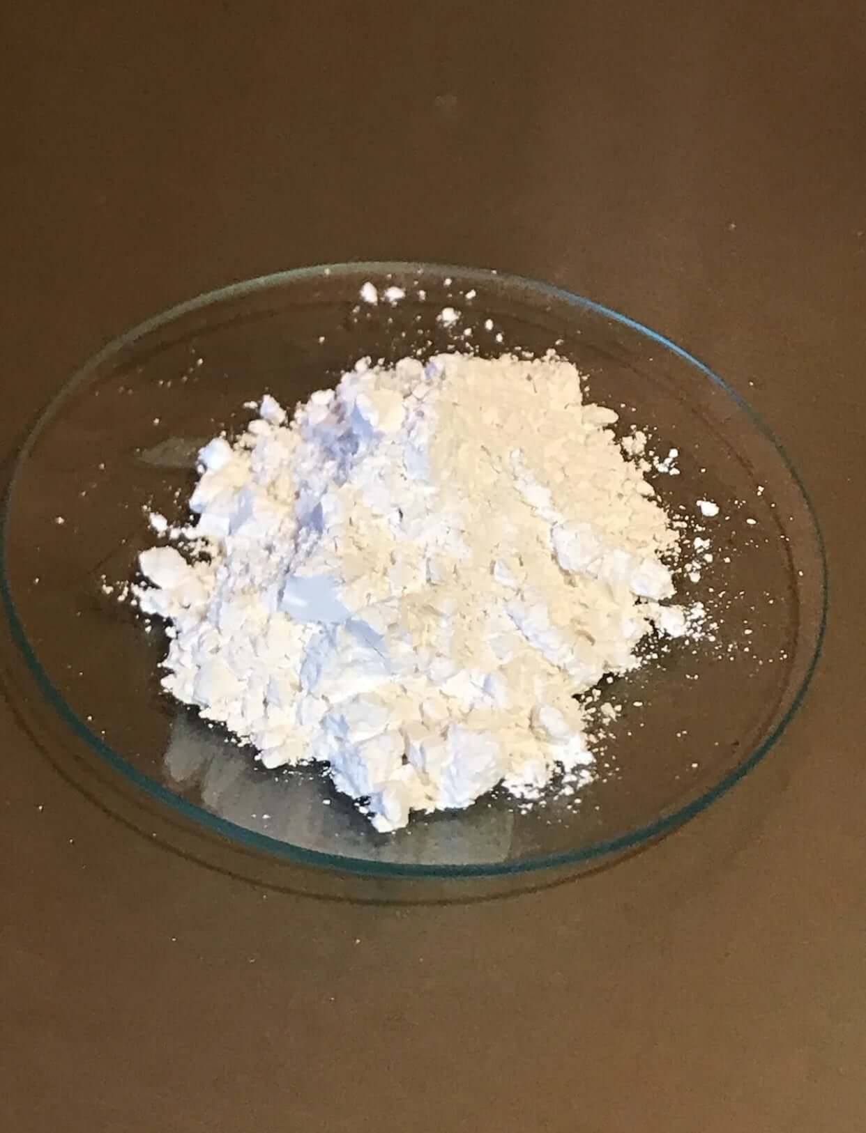 Ultra fine white calcium carbonate powder in a glass dish, showcasing 99.9% purity for industrial use.