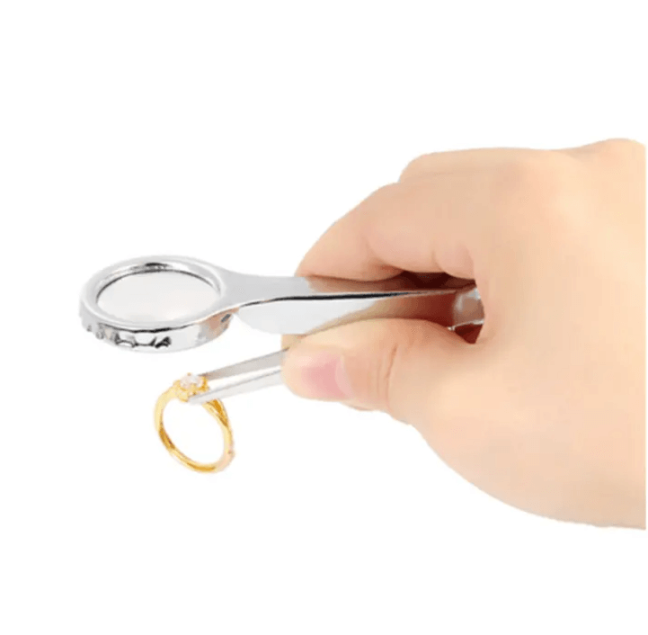 Hand holding a magnifying glass and a golden ring, perfect for examining jewelry details.