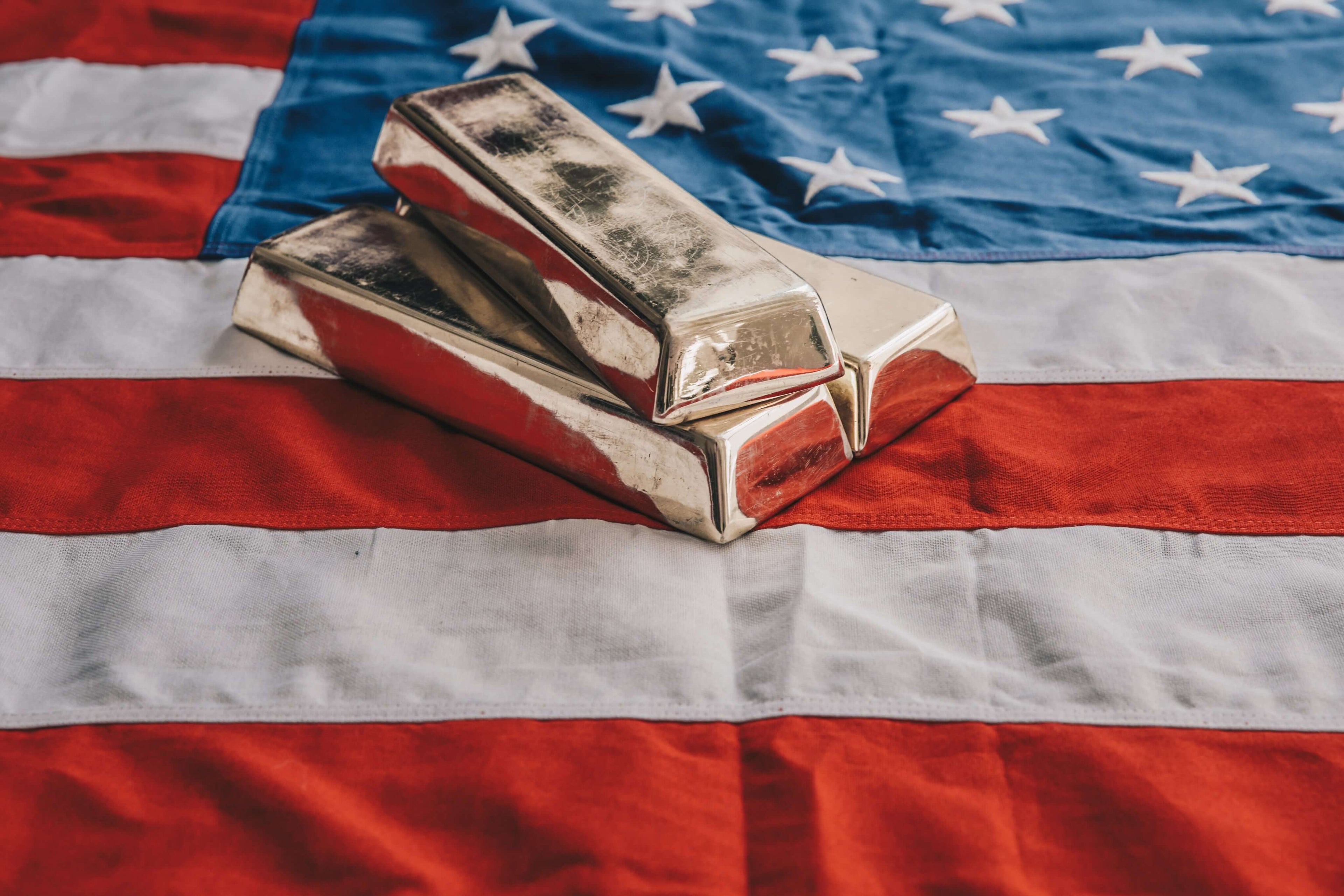 Three gold bars resting on an American flag, symbolizing wealth and patriotism.